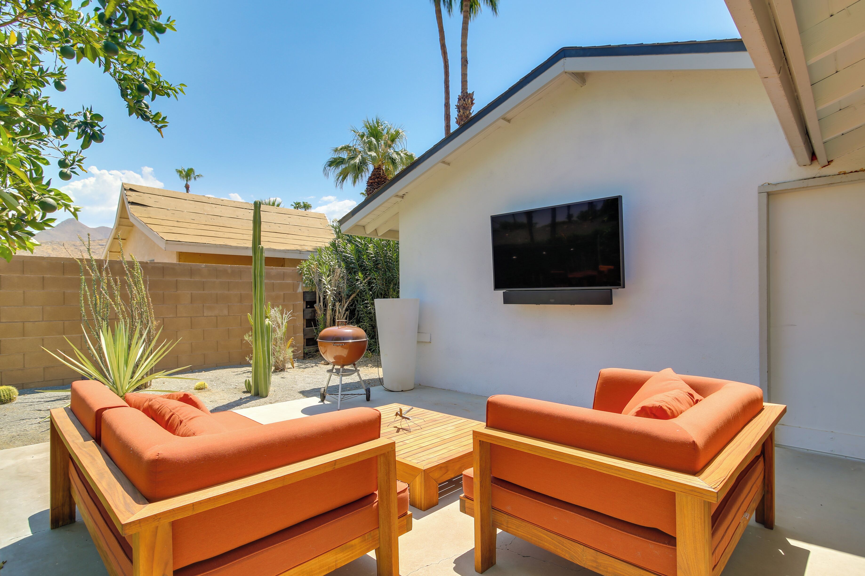 Un patio con mobiliario de madera y un televisor montado en la pared.