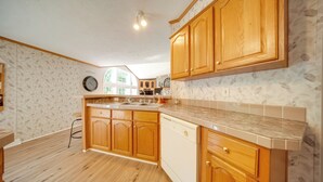 A kitchen with wooden cabinets, a dishwasher, and a countertop. - Secluded Ohio Getaway on 65 Acres! (Andover)