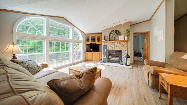 A spacious living room with a large window, a fireplace, and a cozy seating area. - Secluded Ohio Getaway on 65 Acres! (Andover)