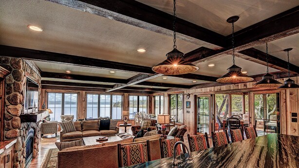 A spacious living area with a large stone fireplace, wooden beams, and a view of the outdoors. - Waterfront Star Lake Cabin, Boat Dock On-site (Star Lake)