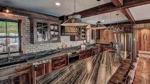 A kitchen with a long island, wooden cabinets, and hanging pendant lights. - Waterfront Star Lake Cabin, Boat Dock On-site (Star Lake)
