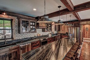 A kitchen with a long island, wooden cabinets, and hanging pendant lights. - Waterfront Star Lake Cabin, Boat Dock On-site (Star Lake)