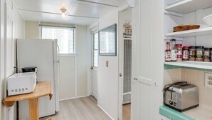 A compact kitchen with a microwave, toaster, and a shelf with jars. - Quaint Avalon Cottage < Half-mi to Beaches! (Avalon)