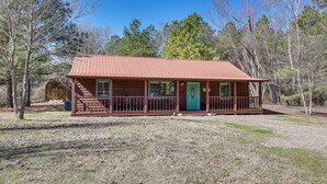 A rustic cabin with a metal roof, a green door, and a porch with railings. - Broken Bow 'starlight Cabin' w/ Private Hot Tub! (Broken Bow)