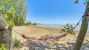 Eine Hängematte, die zwischen Bäumen an einem Sandstrand gespannt ist, mit freiem Blick auf den Ozean.
