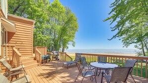 Eine Holzterrasse mit Gartenmöbeln, einem Grill und Blick auf das Wasser.