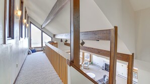 Ein geräumiger Innenraum mit hoher Decke, Holzbalken und Blick auf eine Terrasse.