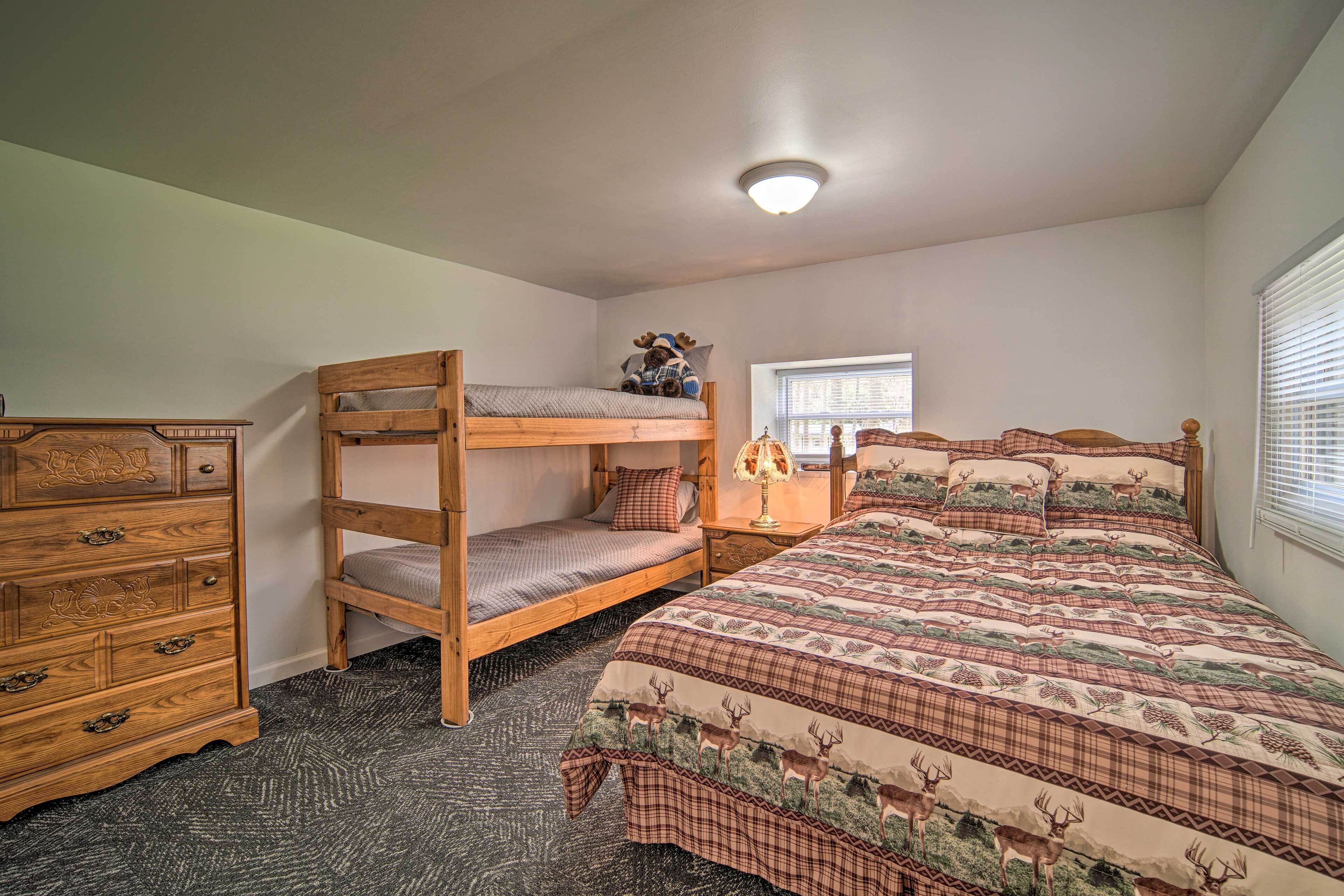 A bedroom with a bunk bed, a dresser, a bedside table with a lamp, and a window with blinds.