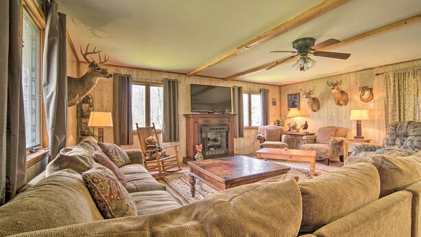 A cozy living room with a fireplace, comfortable seating, and deer and turkey wall decorations. - Rustic & Modern Russell Cabin w/ Grill + Deck (Russell)