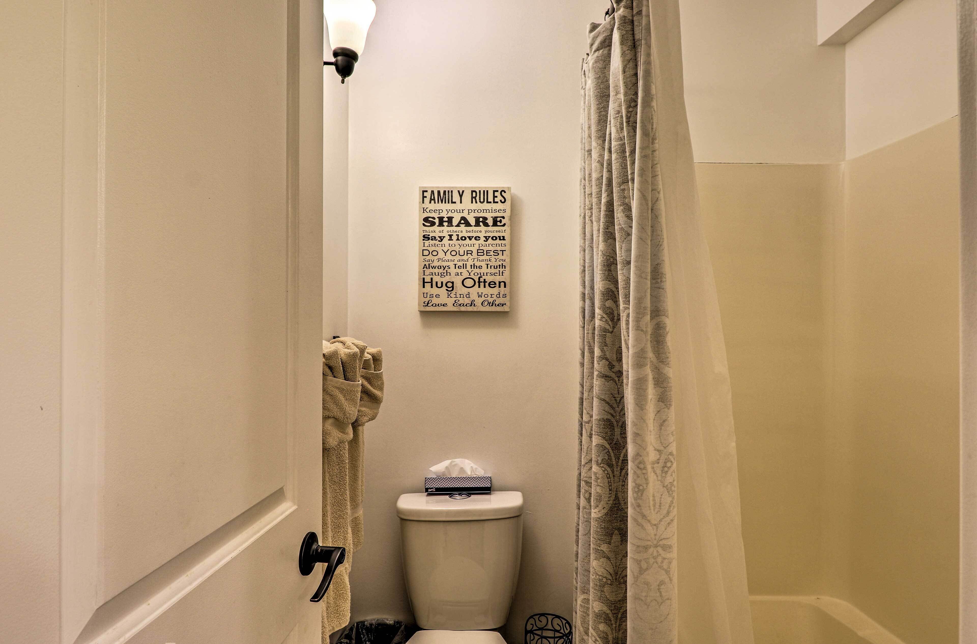 A bathroom with a toilet, a towel rack, and a sign with family rules.