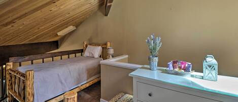 Une chambre à coucher avec un lit en bois, une commode blanche et une petite fenêtre.