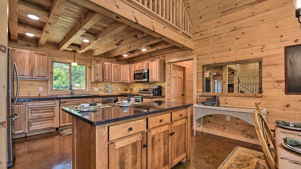 Une cuisine spacieuse avec des meubles en bois, un grand îlot central et un coin repas agrémenté d’un escalier.