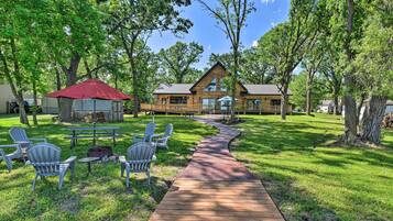 Relax on the deck with a picnic table and Adirondack chairs, surrounded by lush greenery and a fire pit.