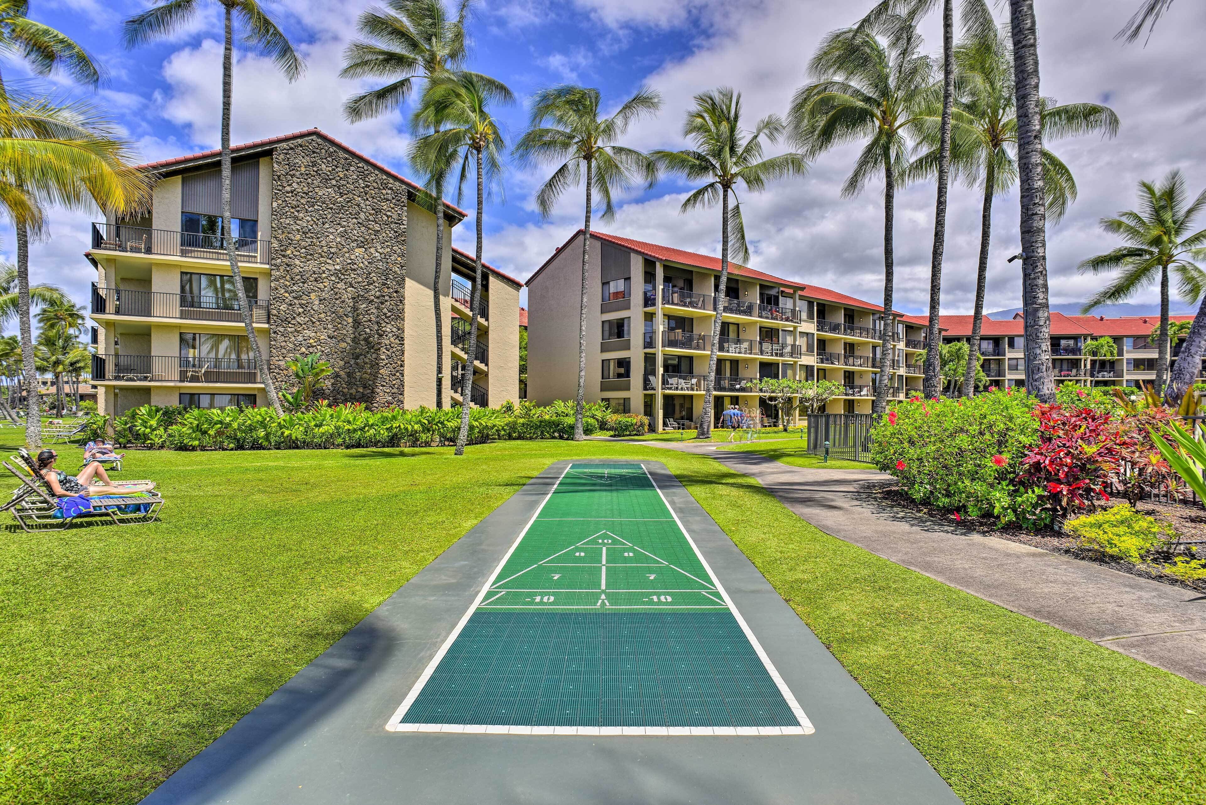 Un hotel con campo da shuffleboard, palme e un edificio con tetto rosso.