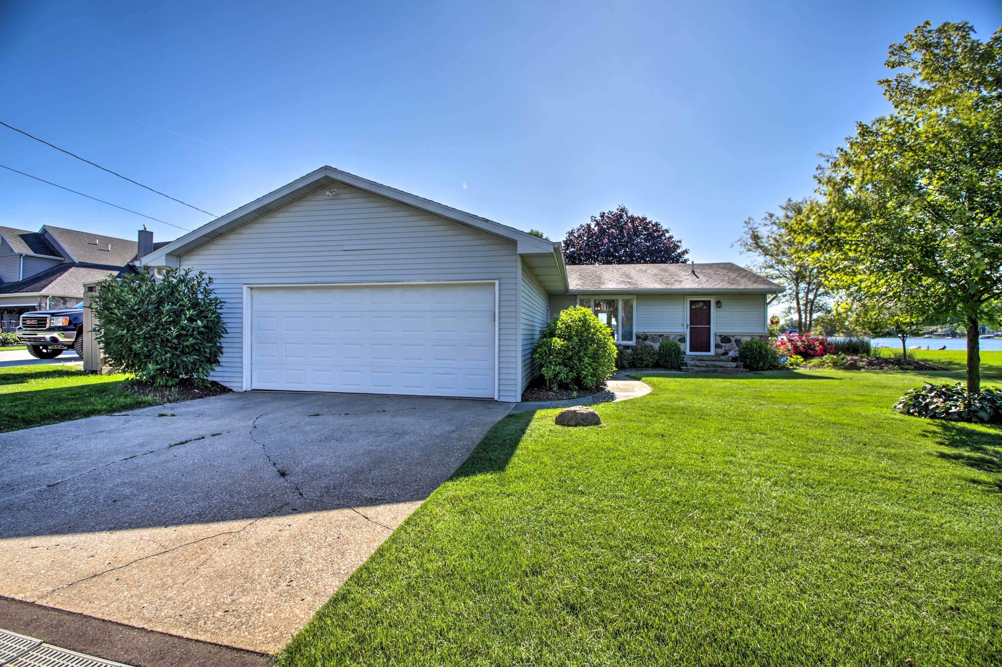 A single-story house with a garage, a well-maintained lawn, and a small garden with various plants and flowers.