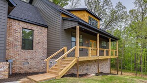 A two-story house with a wooden deck and a staircase leading to a second-floor balcony.