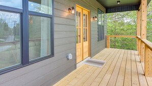 A wooden deck with a glass door leading to a covered porch.