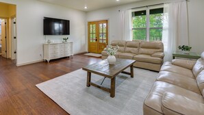 A living room with a wooden coffee table, beige sofa, and a TV mounted on the wall.