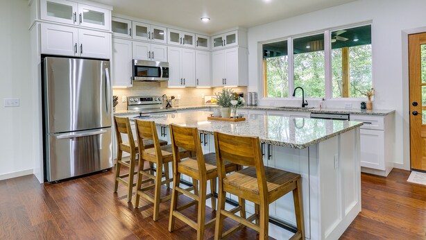 A modern kitchen with white cabinets, stainless steel appliances, and a central island with bar stools.