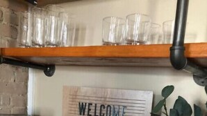Une pancarte de bienvenue pour la suite Mill Street, une machine à café et un vase en verre avec une plante.
