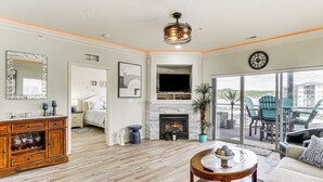 Un salon spacieux doté d’une cheminée, d’un téléviseur et d’un balcon avec des meubles d’extérieur.