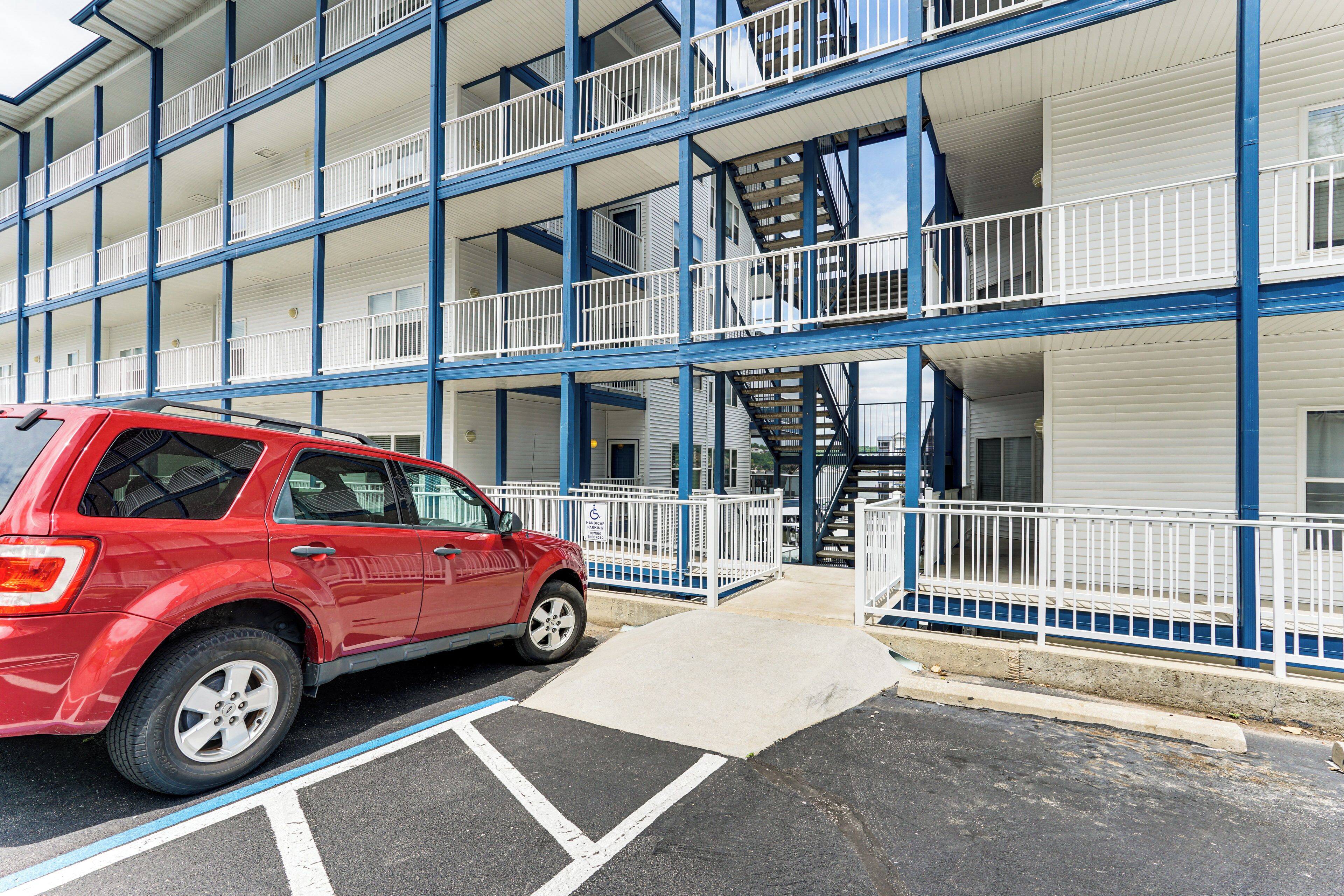 A multi-story building with a red car parked in front.