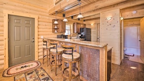 A wooden cabin interior with a bar area, kitchen, and a door. - Sunny Forest Cabin w/ Views of Pikes Peak Mtn! (Florissant)