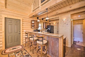 A wooden cabin interior with a bar area, kitchen, and a door.