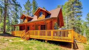 A log cabin with a wooden deck and a covered porch. - Sunny Forest Cabin w/ Views of Pikes Peak Mtn! (Florissant)