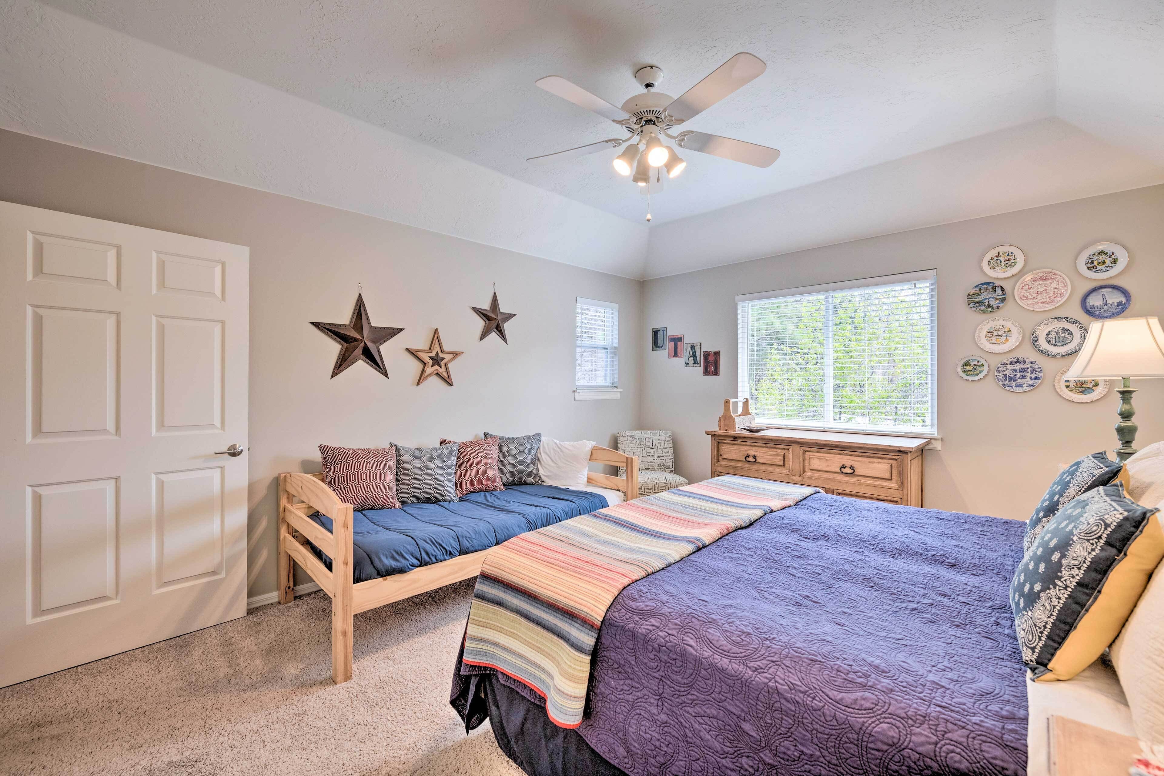 A bedroom with two beds, a ceiling fan, a window, and wall decorations.