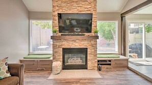 A modern living room with a stone fireplace, a flat-screen TV mounted above it, and a seating area with a bench and cushions. - 'wasatch Basecamp' w/ Hot Tub: Hike & Explore! (Salt Lake City)