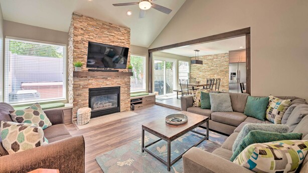 A spacious living room with a stone fireplace, a flat-screen TV, and a ceiling fan. - 'wasatch Basecamp' w/ Hot Tub: Hike & Explore! (Salt Lake City)
