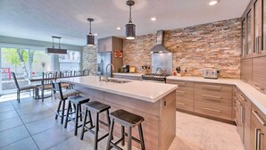 A modern kitchen with a large island, bar stools, and a stone accent wall. - 'wasatch Basecamp' w/ Hot Tub: Hike & Explore! (Salt Lake City)