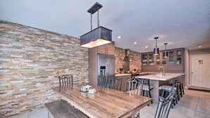A modern kitchen with a large island, stainless steel appliances, and a rustic stone wall. - 'wasatch Basecamp' w/ Hot Tub: Hike & Explore! (Salt Lake City)