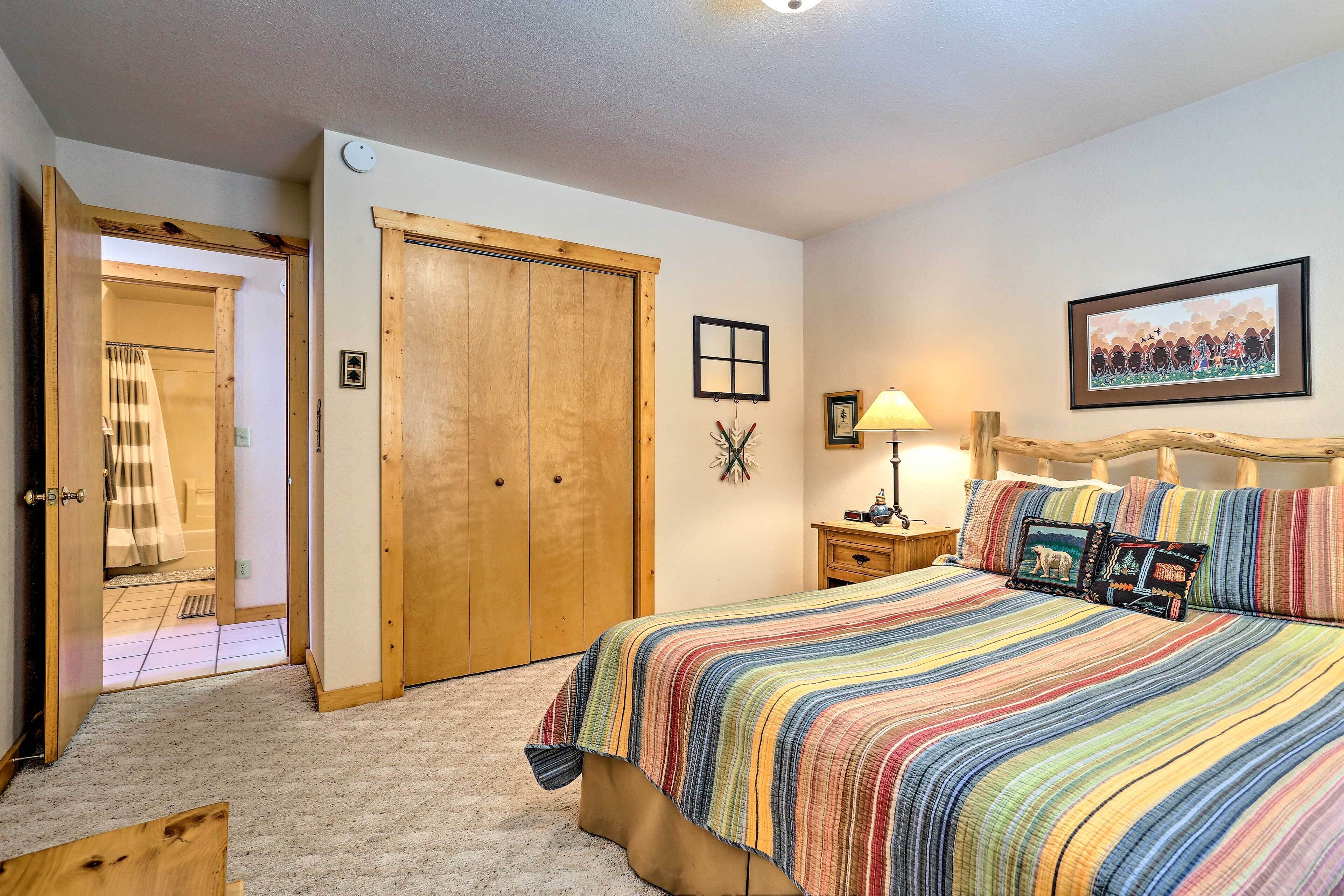 A bedroom with a large bed, wooden wardrobe, and a door leading to a bathroom.