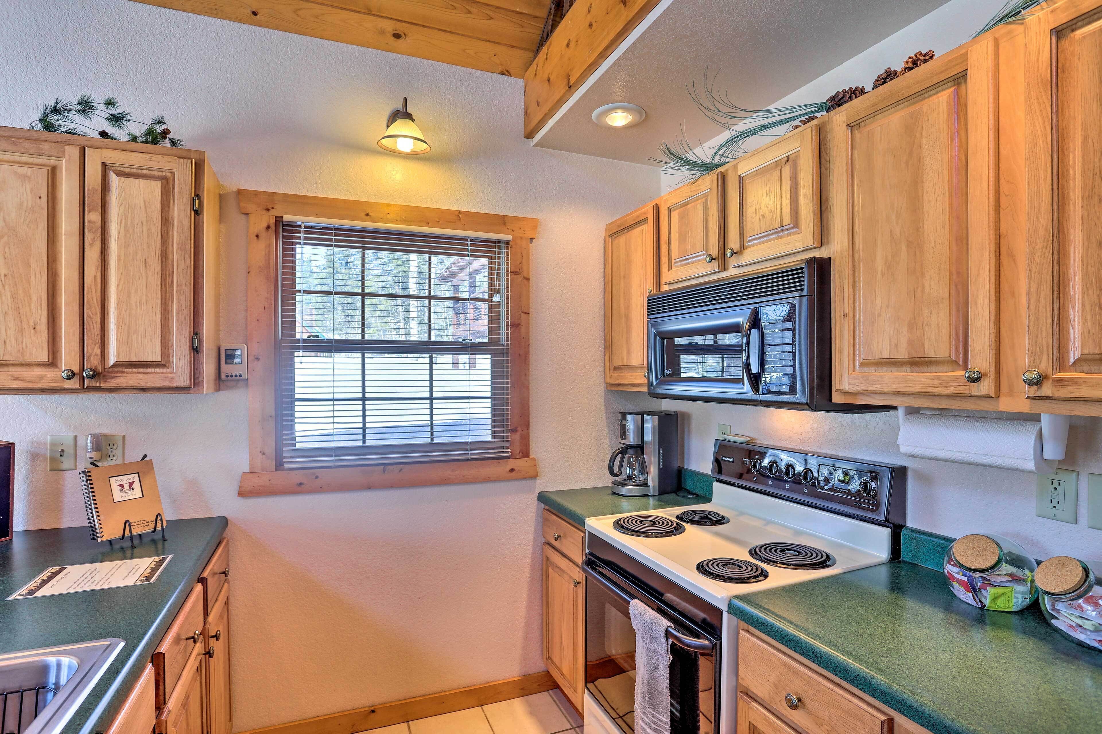 A kitchen with wooden cabinets, a stove, a microwave, and a window with blinds.