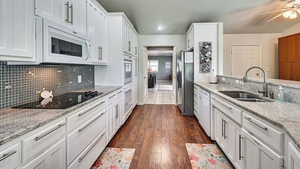 A kitchen with white cabinets, a microwave, a refrigerator, and a sink. - Waterfront Kingsland Home With Pool + River Access (Kingsland)