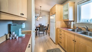 Eine kleine Küche mit Holdekor, einer integrierten Kaffeemaschine, einem Kühlschrank und einem Fenster mit Blick hinaus.
