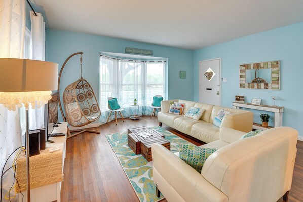 A living room with a white sofa, a hanging chair, a coffee table, and a lamp.