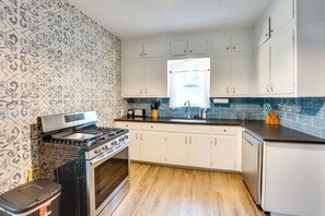 A kitchen with white cabinets, a stove, and a dishwasher.