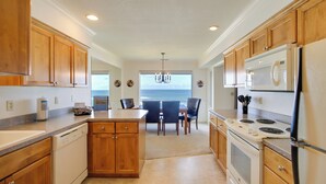 A spacious kitchen with wooden cabinets, a central island, and a view to the dining area. - Lincoln City Vacation Rental w/ Pool & Ocean Views (Gleneden Beach)