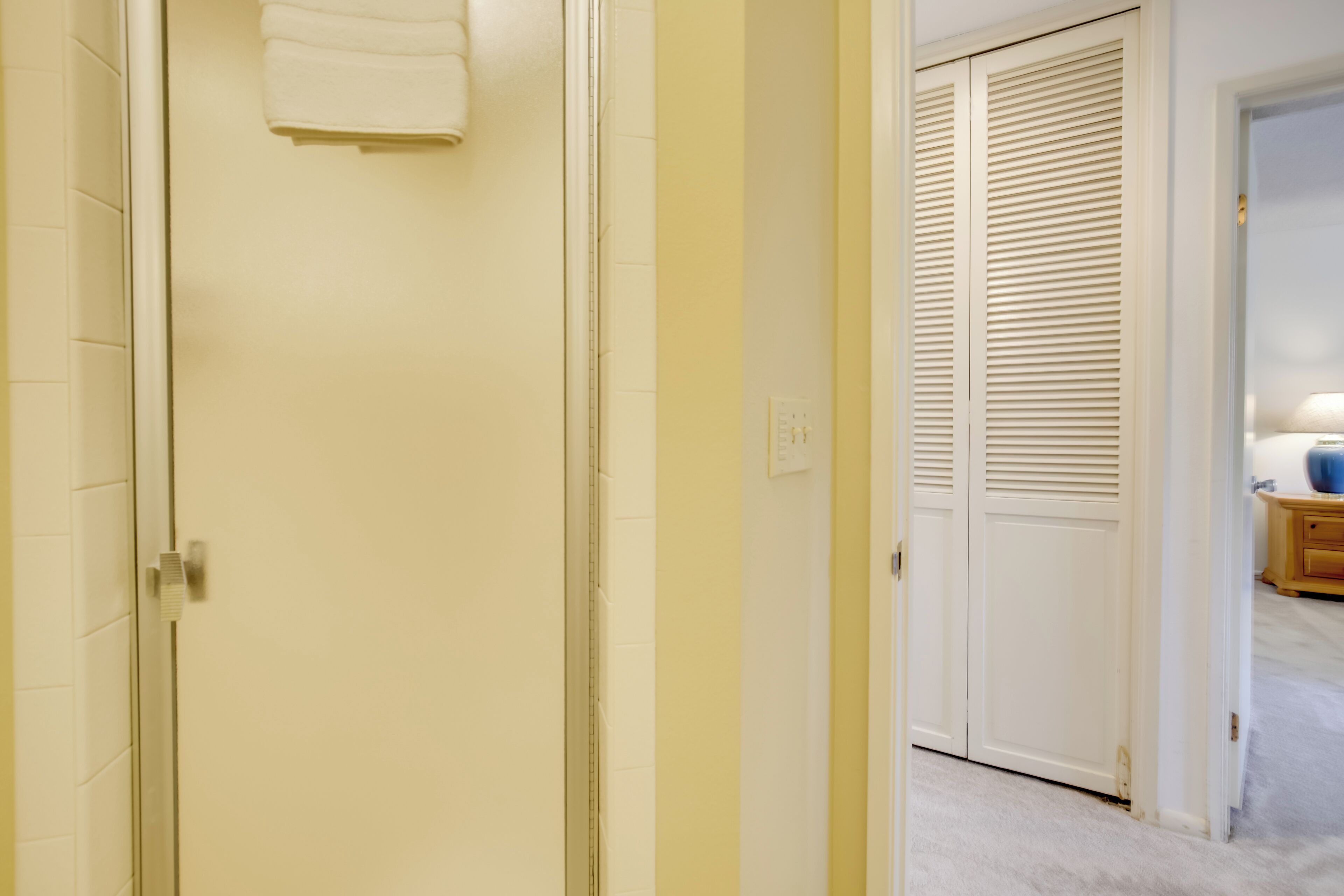 Ein Flur mit geschlossener Tür, einem Handtuch an der Wand und einem Schrank mit Klappläden.