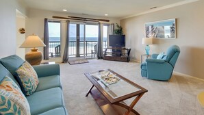 A living room with a sofa, a coffee table, a TV, and a chair. - Lincoln City Vacation Rental w/ Pool & Ocean Views (Gleneden Beach)