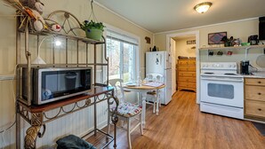 Une cuisine équipée d’un four à micro-ondes posé sur une étagère, d’un réfrigérateur, d’un four et d’une table à manger avec des chaises.