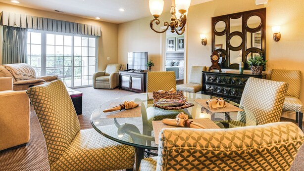 A spacious living room with a glass coffee table, patterned armchairs, a sofa, and a television. - Branson Condo w/ Pool Access & Views, 3 Mi Dtwn! (Branson)