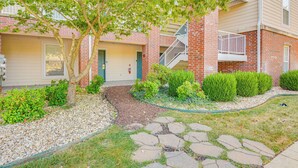 A residential building with a brick facade, a front door, a small garden with a tree and shrubs, and a stone pathway leading to the entrance. - Branson Condo w/ Pool Access & Views, 3 Mi Dtwn! (Branson)