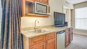 A kitchen with wooden cabinets, a microwave, a dishwasher, a sink, and a television. - Branson Condo w/ Pool Access & Views, 3 Mi Dtwn! (Branson)