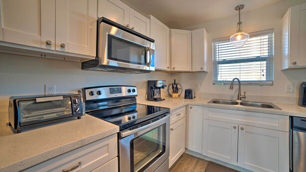 A modern kitchen with white cabinets, a stainless steel microwave, a toaster, an oven, and a coffee maker. - Mexico Beach Home w/ Balcony - Steps to Beach (Port St. Joe)