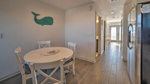 A dining area with a round table, white chairs, and a teal whale wall decoration. - Mexico Beach Home w/ Balcony - Steps to Beach (Port St. Joe)