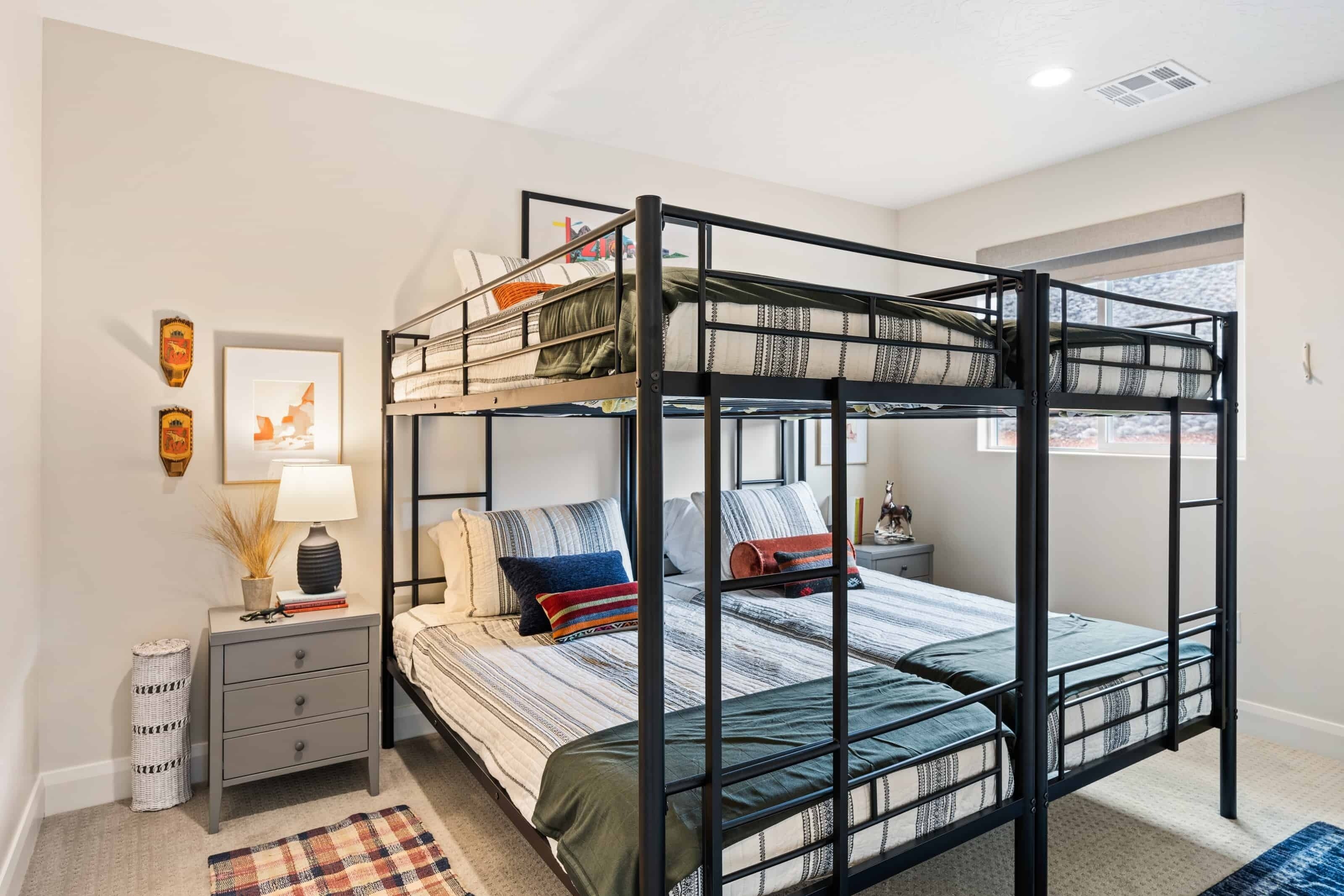 A bunk bed room with a small bedside table, a lamp, and a framed picture on the wall.